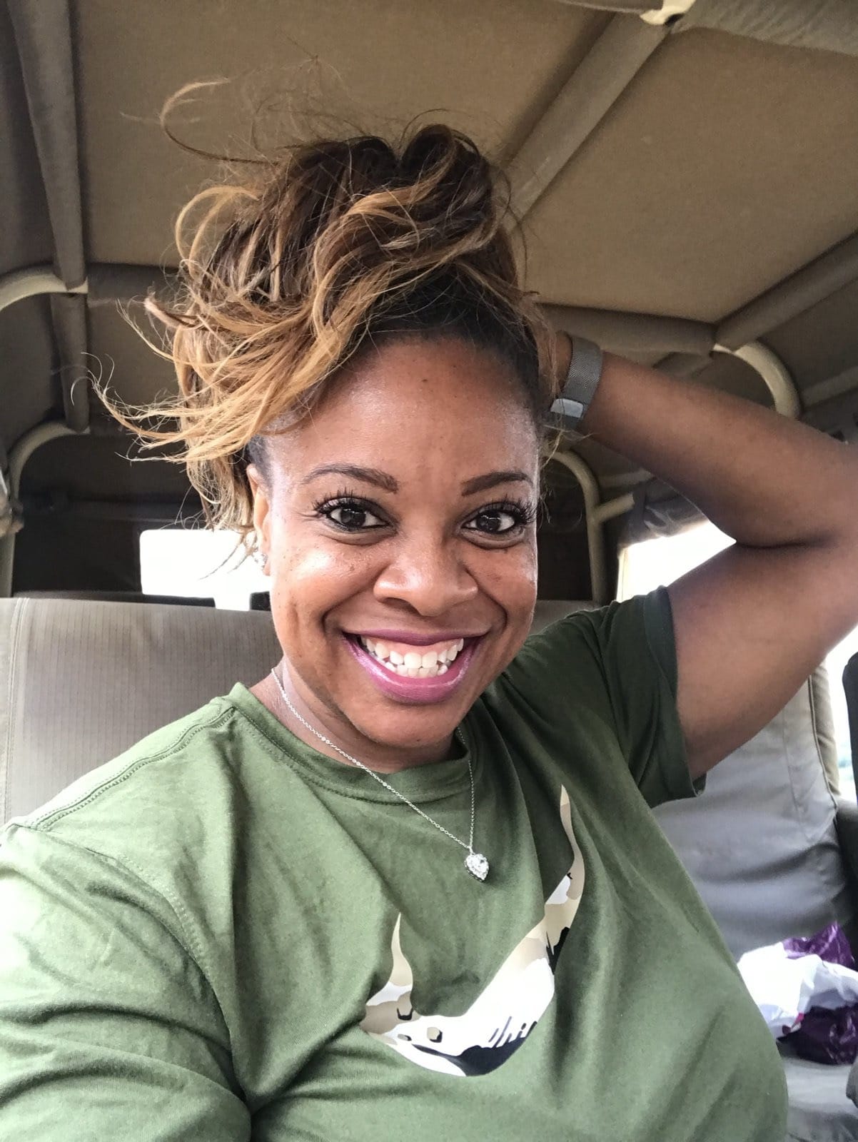 Claire smiling in an olive safari tee inside a game drive vehicle in Kenya
